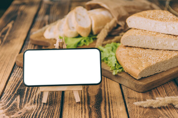 Mock up smartphone on background with fresh bread on a wooden background.