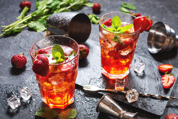 Strawberry mojito and ingredients on black stone background