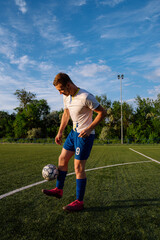 Young male soccer player juggles a ball on a soccer field.