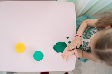 Little girl with a lovely face play with clay molding shapes, learning through playing with colored plasticine developing creativity