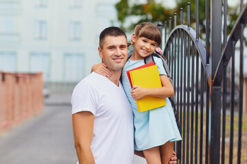 Schoolgirl with father smiling outdoors at school.