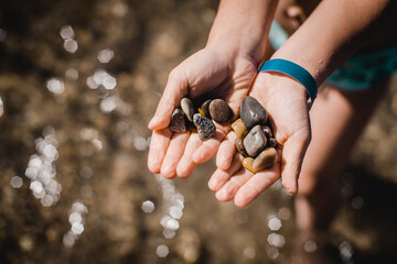 A child holds a few sea stones in his hands. It is a moment of the summer holidays