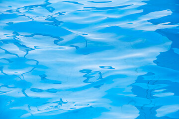 Repeating summer pattern of photographed, living water surfaces in a pool, with the emphasis on light refraction where you can see the sprinkled ground moving along with the waves