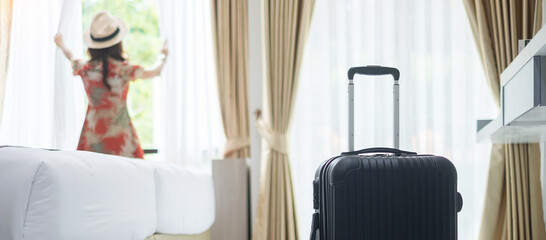 Luggage in modern hotel room with happy young adult female relaxing nearly window, asian woman...