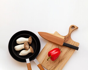 New frying pan set, wooden cutting board and kitchen knife isolated on white background with copy space. Top view.
