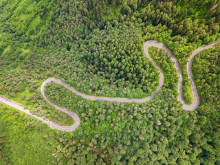 Beautiful aerial view of winding roadmountain cutting through forest landscape in summer time. Aerial view by drone . Romania	