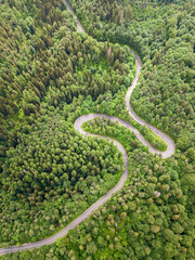 Beautiful aerial view of winding roadmountain cutting through forest landscape in summer time. Aerial view by drone . Romania	