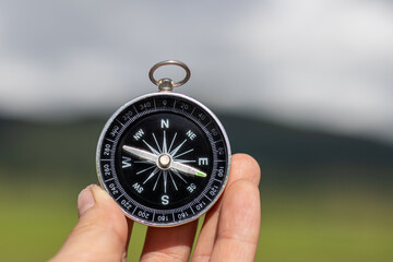Hand holding a compass with natural blurred green background.. - travel and transportation concept.