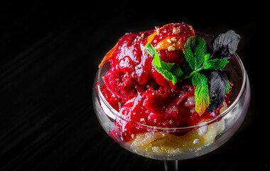 fruit sorbet ice cream in a glass bowl on black wooden table background