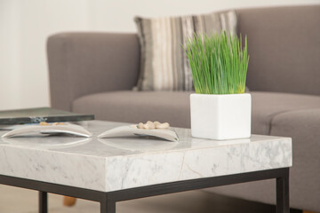 marble table detail with a white  glass vase, background a gray sofa