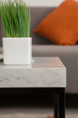 marble table detail with a glass vase on background sofa, close up of living room
