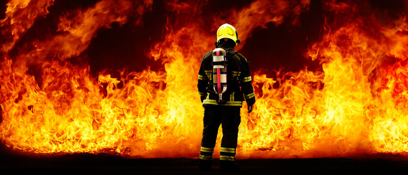 Rear of firefighter with fire uniform and equipment on flame background with copy space