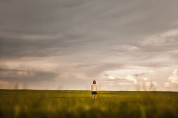 Obraz na płótnie Canvas Woman stands alone in the field, concept of new life, concept of loneliness