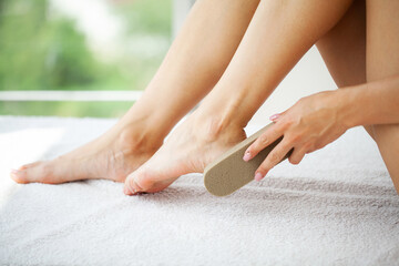Woman cleans the heel of the foot with pumice