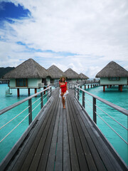 beautiful girl in swimsuit posing on dock, tropical resort in background