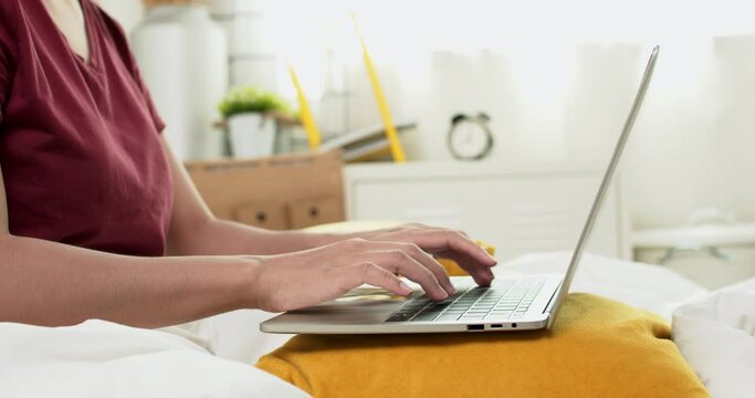 close up hand of woman typing on laptop on bed, work from home concept