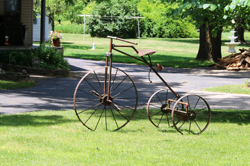 Fototapeta na wymiar a vintage antique rusty three wheel bicycle bike trike parked on a grass lawn