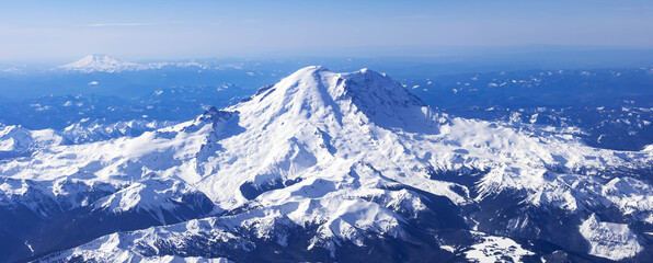 Fototapeta premium Aerial View of Idaho mountains from the sky while inside an airplane. View of brown mountains and trees covered with snow