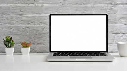 Laptop with blank screen on white table with coffee cup. Home interior or office background.