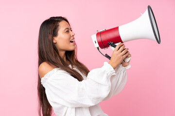 Young Brazilian girl over isolated pink background shouting through a megaphone