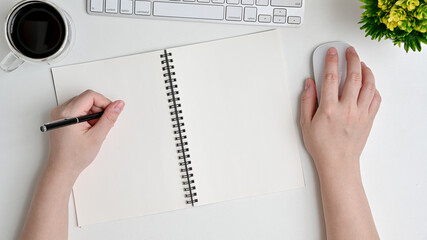 Businesswoman writes in the planner. Workspace with computer, keyboard and coffee cup on white...