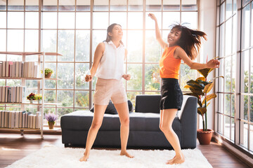 Two asian female friend dancing in living room at home, Happy stay home concept