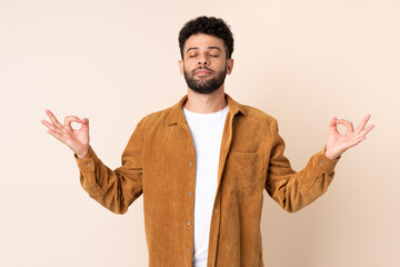 Young Moroccan man isolated on beige background in zen pose