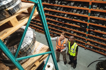 Two male factory workers with digital tablet checking stock at the factory