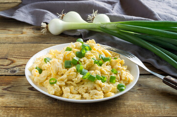 scrambled eggs on a white plate with green onions.