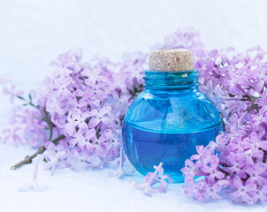 Obraz na płótnie Canvas Glass bottle with aromatic oil and lilac flowers for Spa and aromatherapy. Selective focus