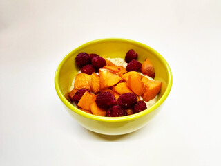 Yellow plate with porridge and fruits. Apricot and cherry