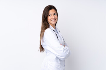 Teenager girl over isolated white background wearing a doctor gown and with arms crossed