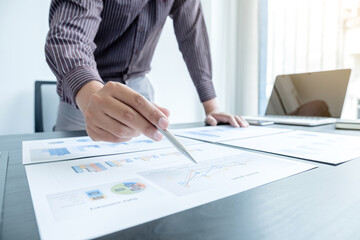 The hands of a male businessman are analyzing and calculating the annual income and expenses in a financial graph that shows results To summarize balances overall in office