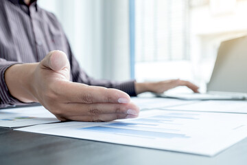 The hands of a male businessman are analyzing and calculating the annual income and expenses in a...