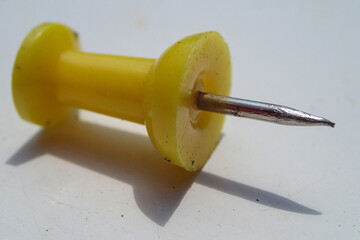 Closeup macro photograph of thumbtack on white table with shadow