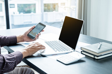Fototapeta premium The hands of a male businessman are analyzing and calculating the annual income and expenses in a financial graph that shows results To summarize balances overall in office