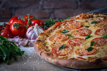 Mozzarella pizza and cooking ingredients: tomatoes, basil, garlic on wood table background