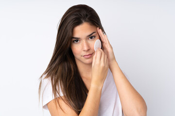 Teenager girl over isolated background with cotton pad for removing makeup from her face