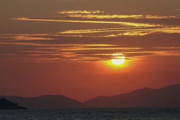 Orange sunset over the ocean with mountain skyline