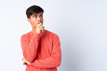 Handsome man over isolated blue background having doubts and thinking