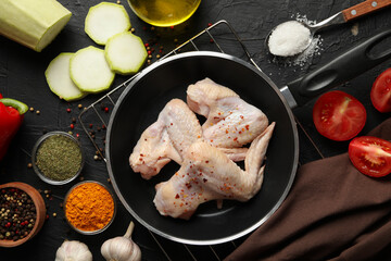 Raw chicken meat and spices on black background, top view. Cooking chicken