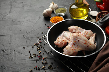 Raw chicken meat and spices on black background, space for text