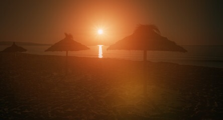 Dark sunset photo umbrella silhouette, early morning on the beach, you can see the sunrise over the...