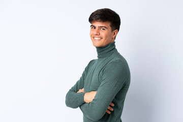 Handsome man over isolated blue background with arms crossed and happy