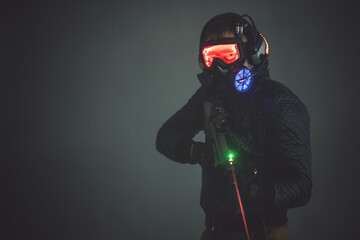 Futuristic soldier in led light helmet with a rifle on dark background.