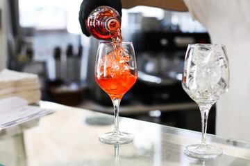 A process of making traditional Italian aperitif - Aperol Spritz in a bar, pouring orange drink...