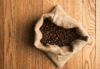 Coffee beans in canvas sack on wooden table