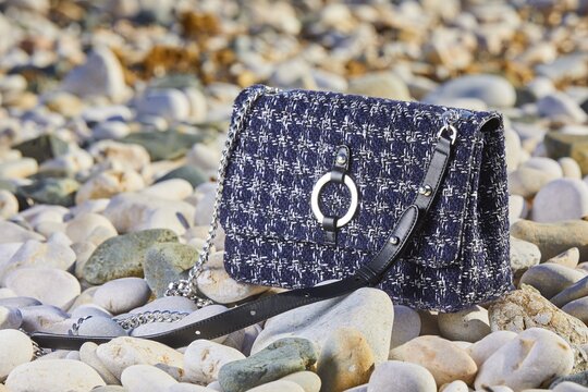 Closeup shot of a little checkered bag on rocks under the light with a blurry background