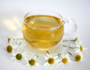 Cup and saucer of chamomile tea surrounded by flowers