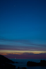 colorful purple pink sunset on rocky beach with cloudy sky